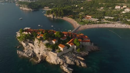 drone view of stone houses with orange tiled roofs on Sveti Stefan island in the Adriatic Sea, with