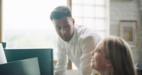 Mitarbeiter sitzen und stehen an Computern in einem modernen, gut beleuchteten Designbüro