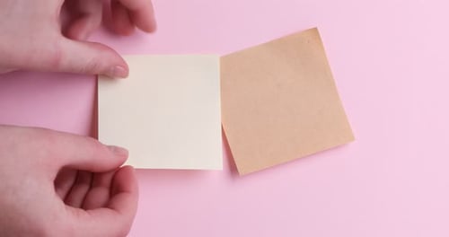Hands Place Square Paper on Pink Background Top View