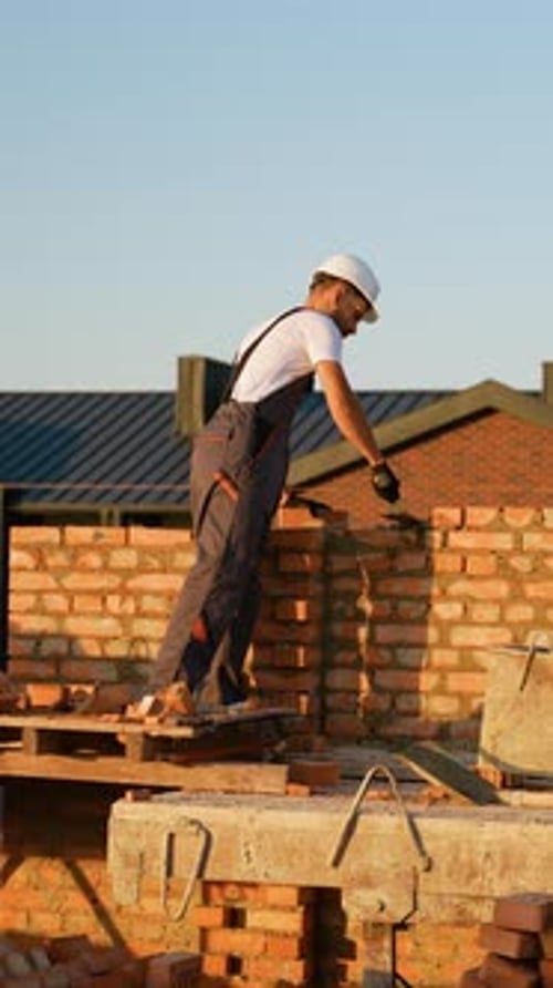 Skilled Worker Laying Bricks at Construction Site