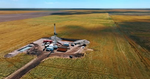 Approaching the oil production site in the immense field. Derrick in the center of location