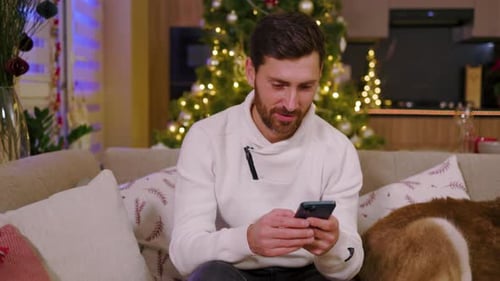 Man Using Mobile Phone on Sofa at Christmas