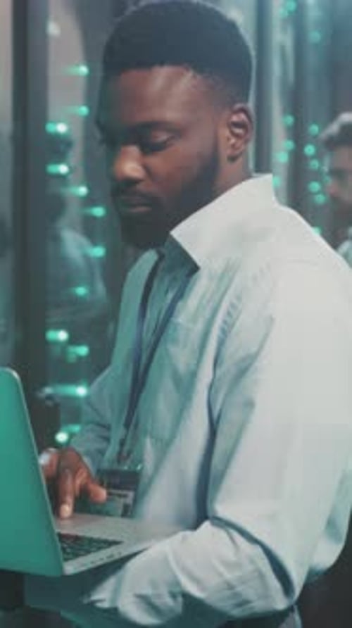 Man Works with Laptop in Server Room