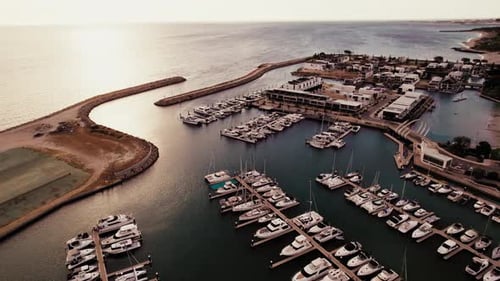 Marina filled with yachts at sunset near coastline
