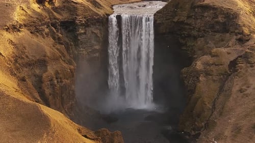 Aerial view of Skógafoss waterfall, Iceland, with a vibrant river and green hills