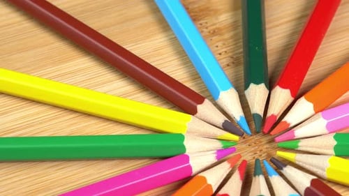 Colorful pencils rotate as sun rays background. Rainbow pencils for drawing. Assortment of colored