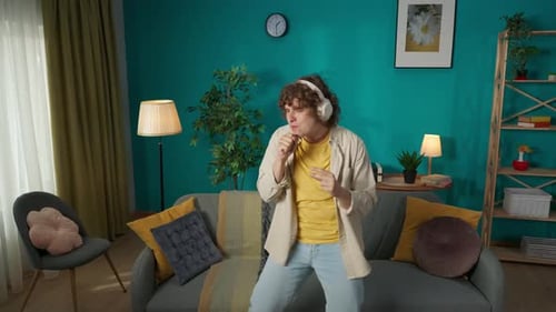 Man in Casual Clothing with Headphones on Dancing Like a Rock Star in the Living Room Listening to