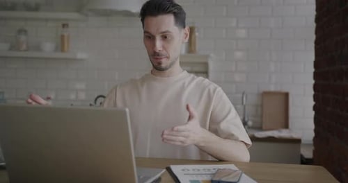 Man Video Conferencing on Laptop in Modern Kitchen