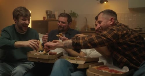 Four Friends are Sitting on the Sofa and Actively Eating Pizza From Paper Boxes While Relaxing and