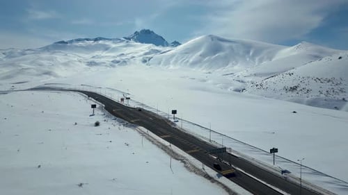 Aerial View of Winding Highway Through Snow-Covered Mountains