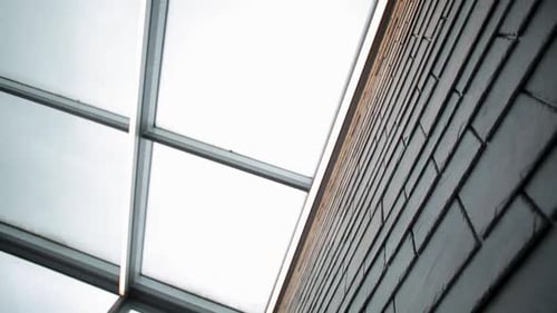 Glass ceiling and brick wall from a low angle, creating an abstract urban look
