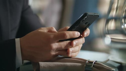 Male Hands Using Smartphone at Restaurant. Businessman Using Mobile Phone in Restaurant