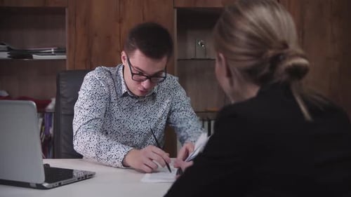 Man Explaining Documents to Woman in Office