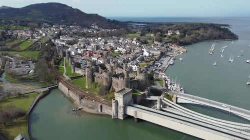 An aerial view of Conwy Castle on a sunny day, flying towards the castle with the town in the backgr