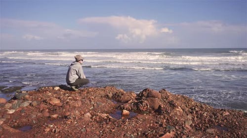 Junger Mann entspannt sich am Rocky Beach im friedlichen Sommerurlaub in der Natur