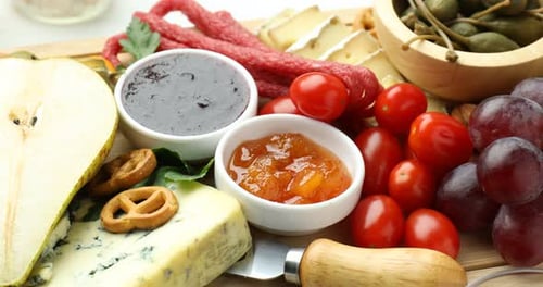 Charcuterie board with many different snacks on table, closeup. Camera moving left