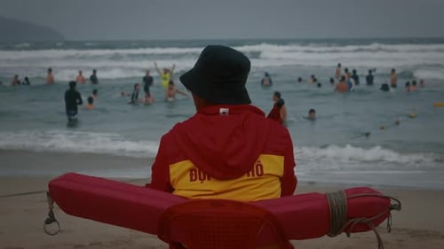 Lifeguard Watching Swimmers with Rescue Buoy on Beach