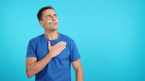 Man with Paint on Face Puts Hand on Chest