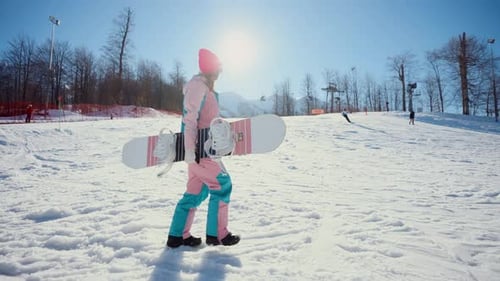 Woman Carries Snowboard on Snowy Mountain Slope