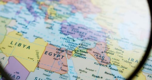 Using a magnifying glass, showing a close-up of the countries in the Middle East such as Israel, Egy