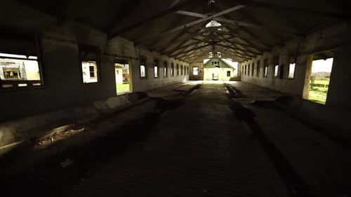 Interior pan from top right to bottom left of an abandonded barn near an insane asylum, dark, creepy