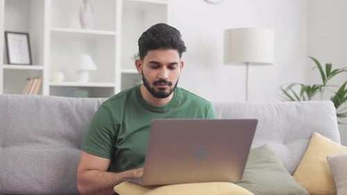 Man Typing on Laptop on Couch at Home