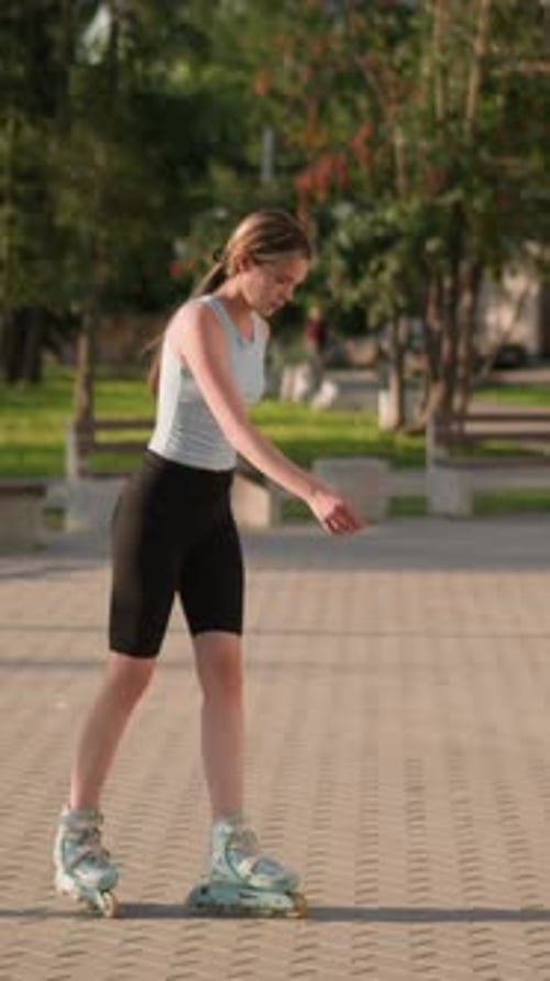 Young Lady Skating Leisurely in Park Surrounded By Greenery and Benches