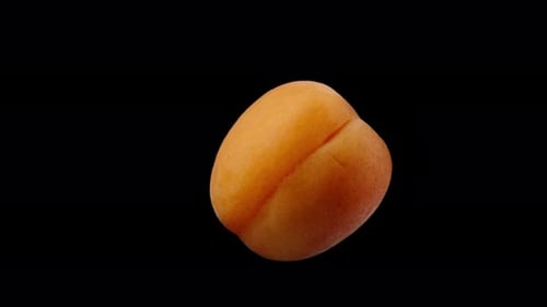 An apricot on a black background rotates in close-up, isolated.