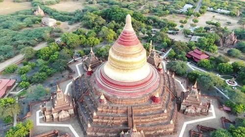 Ancient Buddhist temple in Bagan, Myanmar with more in background. Aerial drone shot.
