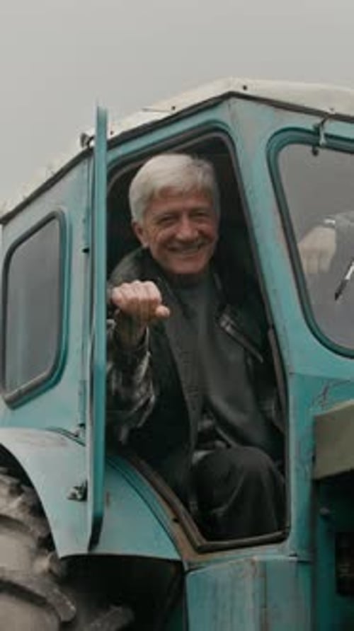 Senior Man Smiling in Blue Tractor on Farm