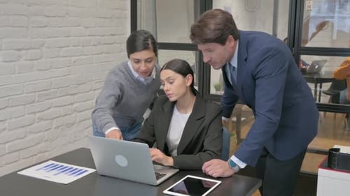 Three Colleagues Collaborating on Project in Office