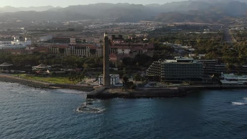 Aerial shot of the Gran Canaria resort on the coast and Maspalomas Lighthouse in the evening. Rotati