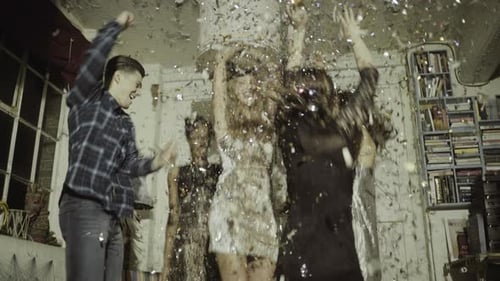 Friends celebrate together as confetti falls inside home