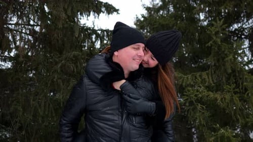 Happy Romantic Couple Enjoying Piggyback Ride in Winter Forest
