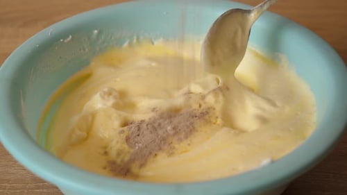 Mixing Brown Powder into Yellow Batter in Bowl