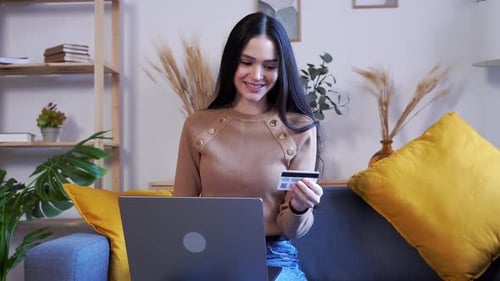 Woman Shops Online Using Credit Card on Laptop