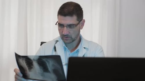 Male Doctor Analyzing The X-Ray Plate With His Laptop. medium shot