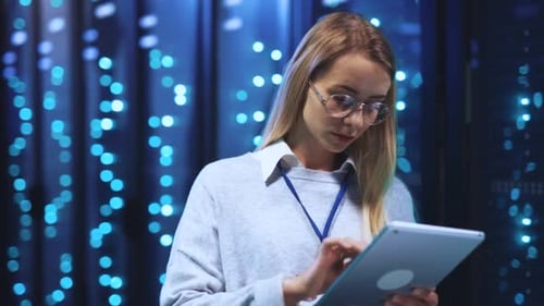 A Professional Woman Confidently Works in a Server Room with Tech