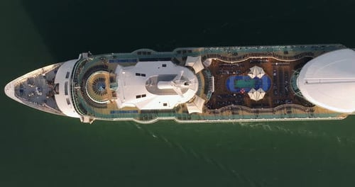Large Cruise Ship with passengers on upper deck cruising at sea.