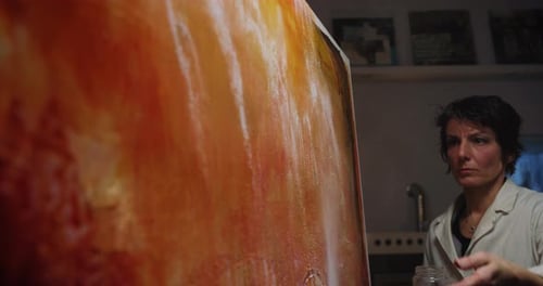 Cinematic shot of female creative artist painter concentrated and inspired painting colorful abstr