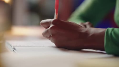 Close-up of Hands Writing in a Notebook