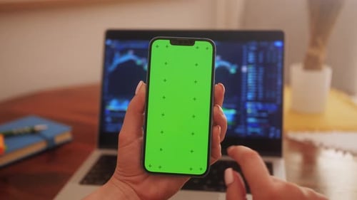 Mãos segurando o smartphone com tela verde no gráfico de movimento da criptomoeda na tela de