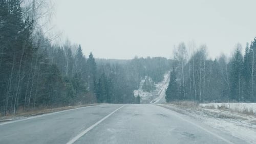 Winter Road FPV Camera Moves Along the Asphalt Road Covered with Snow During the Snow Blizzard