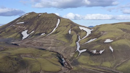 Aerial drone view with a backward left movement, facing a green mountain in Landmannalaugar near Blá