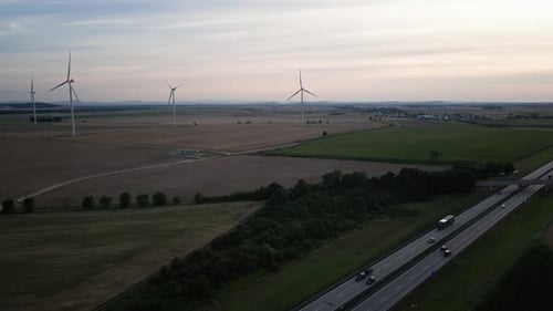 Autobahnstraße mit Autoverkehr und Windmühlengenerator vor Sonnenuntergang