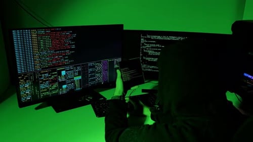 Hooded Hacker examine le Code d'un téléphone pliable sous une cyberlumière verte la nuit