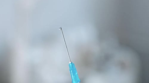 Fluid drips from hypodermic needle in extreme close up