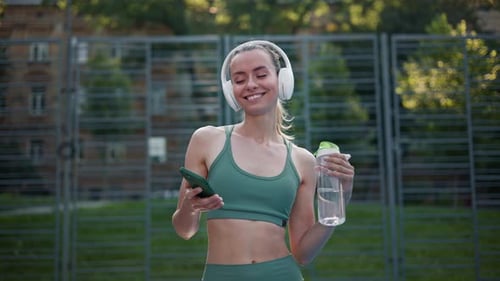Happy Woman Uses Phone After Workout