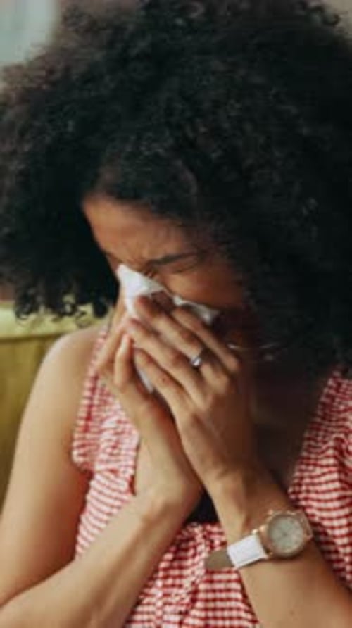 Woman with Allergies Blowing Nose Indoors