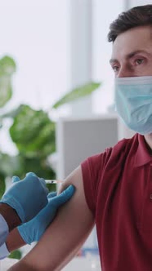 African American Doctor Servicing Male Custome Rin Private Clinic Hospital Doing Vaccination